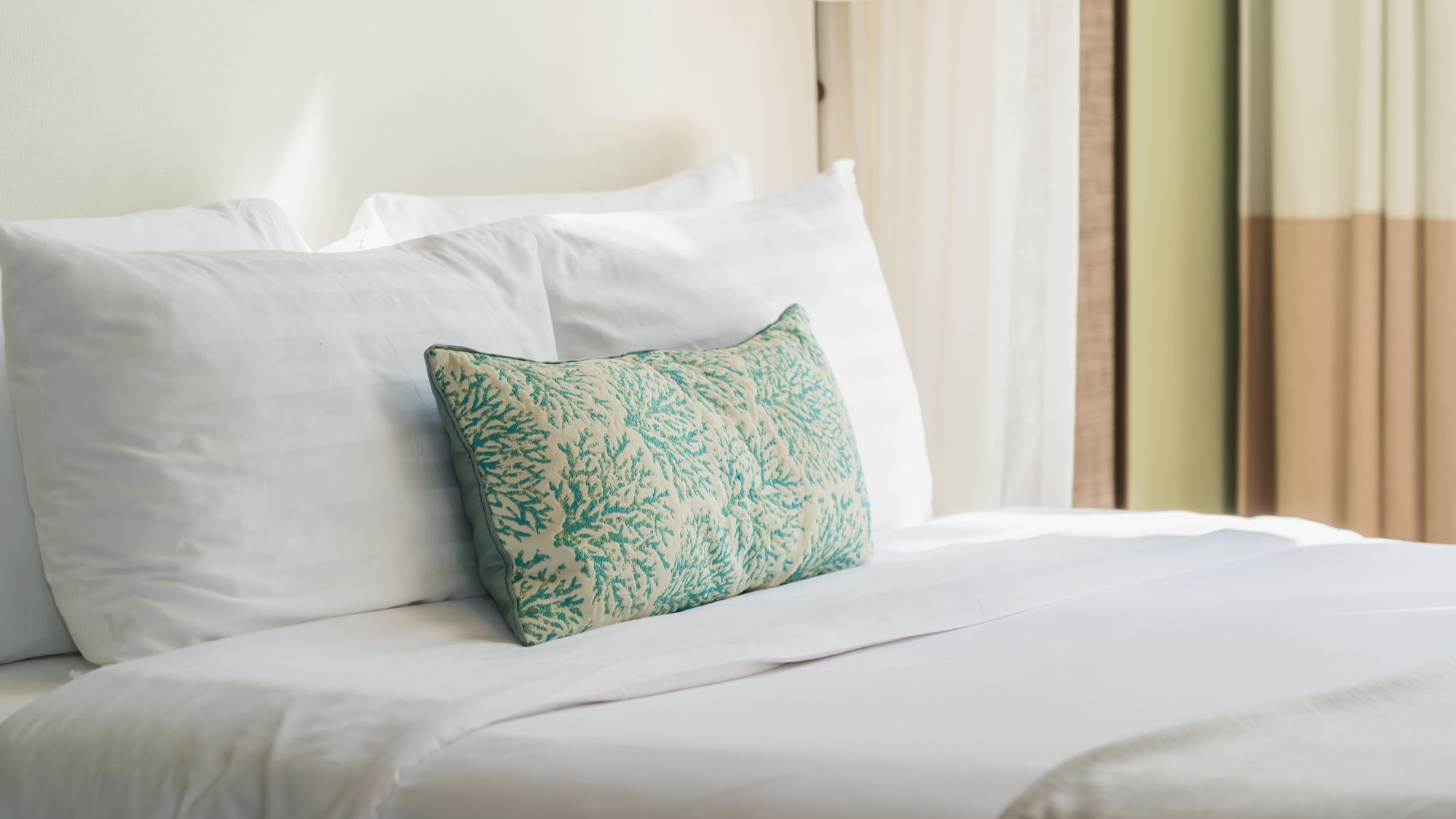 A bedroom with pillows neatly covered in the pillow cover and a deep fitted sheet