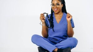 A nurse sitting happily, wearing purple medical jogger scrubs